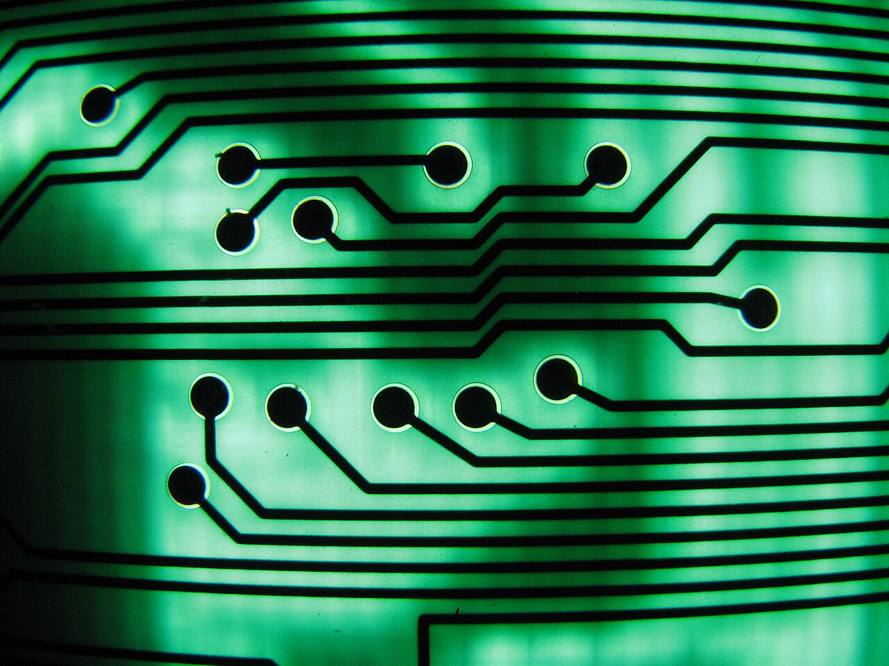 Macro photograph of a green printed circuit board with fine copper traces connecting components