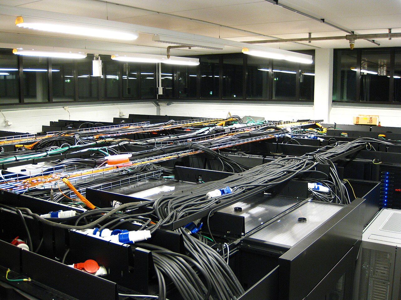 Rows of rack-mounted servers in a secure data hall with overhead cabling